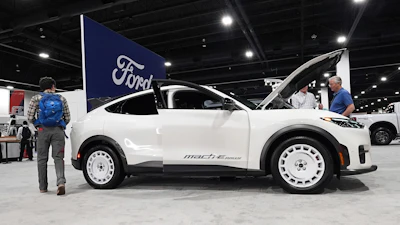 White Mazda MX-5 Miata sports car on display at automotive show with Ford signage visible