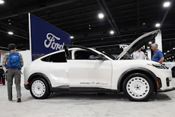 White Mazda MX-5 Miata sports car on display at automotive show with Ford signage visible