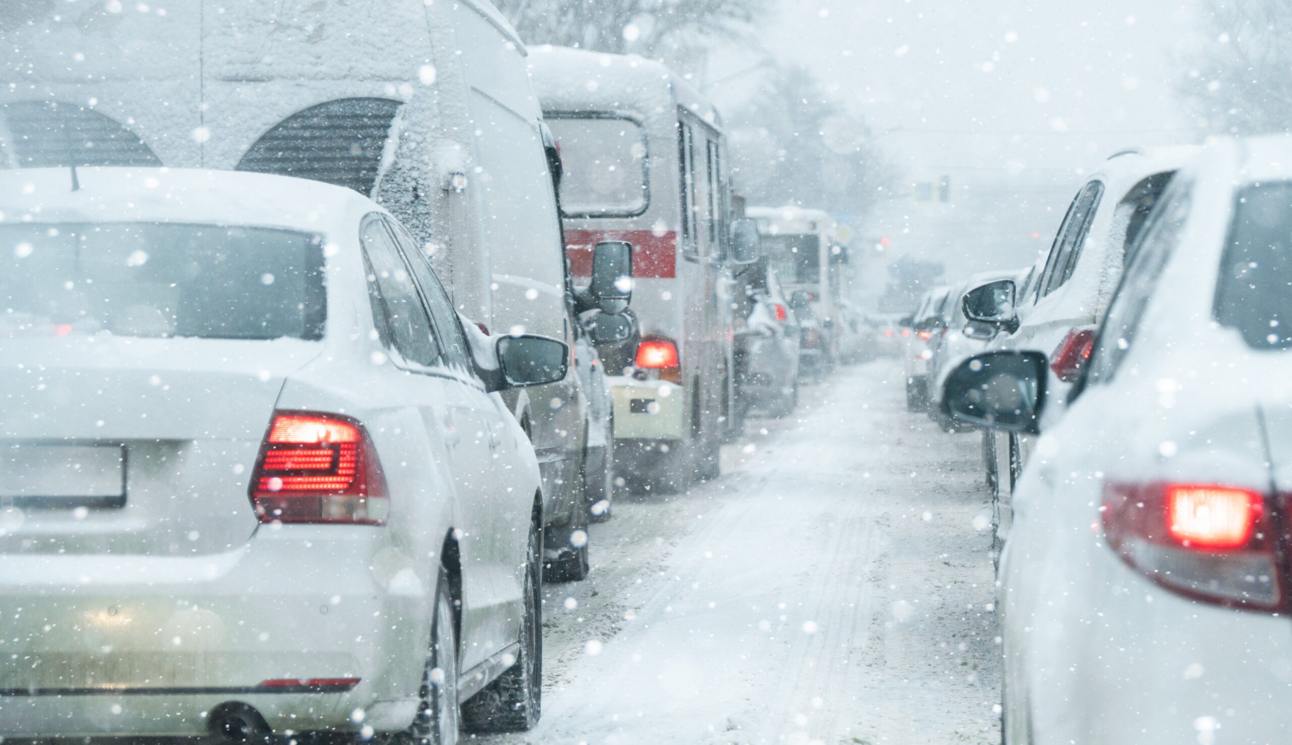 Heavy traffic jam during snowstorm with vehicles displaying brake lights in winter weather conditions