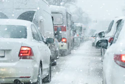 Heavy traffic jam during snowstorm with vehicles displaying brake lights in winter weather conditions