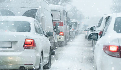 Heavy traffic jam during snowstorm with vehicles displaying brake lights in winter weather conditions