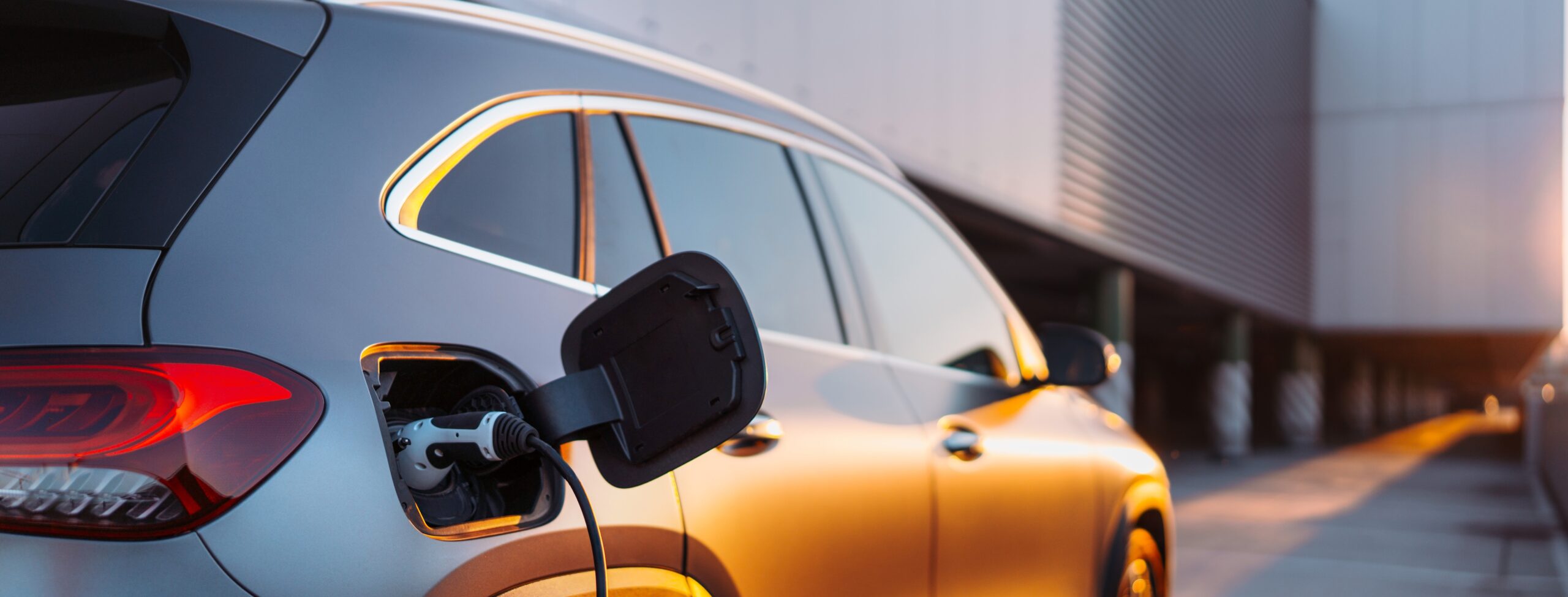 Electric vehicles charging at an outdoor charging station during golden hour