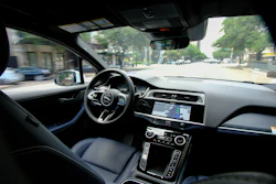 Luxury car interior dashboard with steering wheel and navigation display while driving on urban street