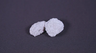 Two white crystalline mineral specimens on dark gray background