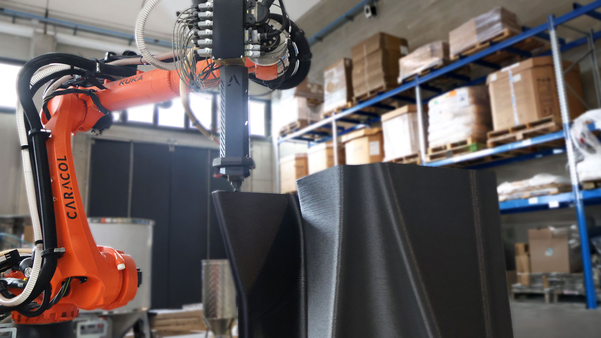 Kuka industrial robotic arm with orange frame operating in warehouse with blue shelving and cardboard boxes