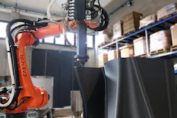 Kuka industrial robotic arm with orange frame operating in warehouse with blue shelving and cardboard boxes
