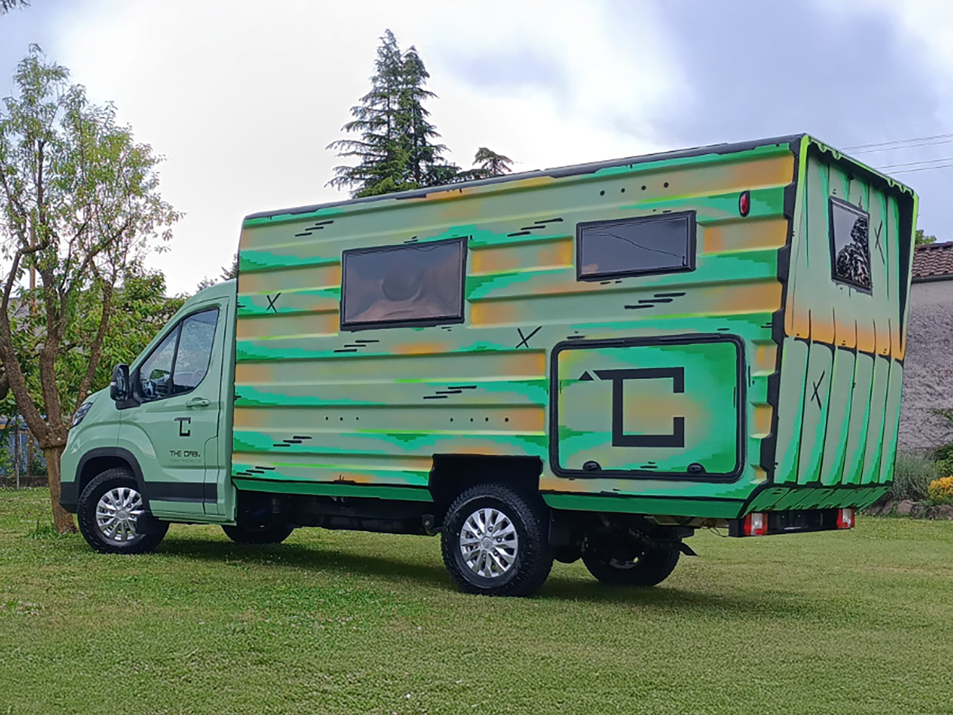 Green and yellow striped motorhome parked on grass with trees in background