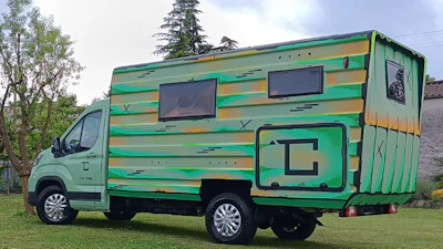 Green and yellow striped motorhome parked on grass with trees in background