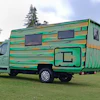 Green and yellow striped motorhome parked on grass with trees in background
