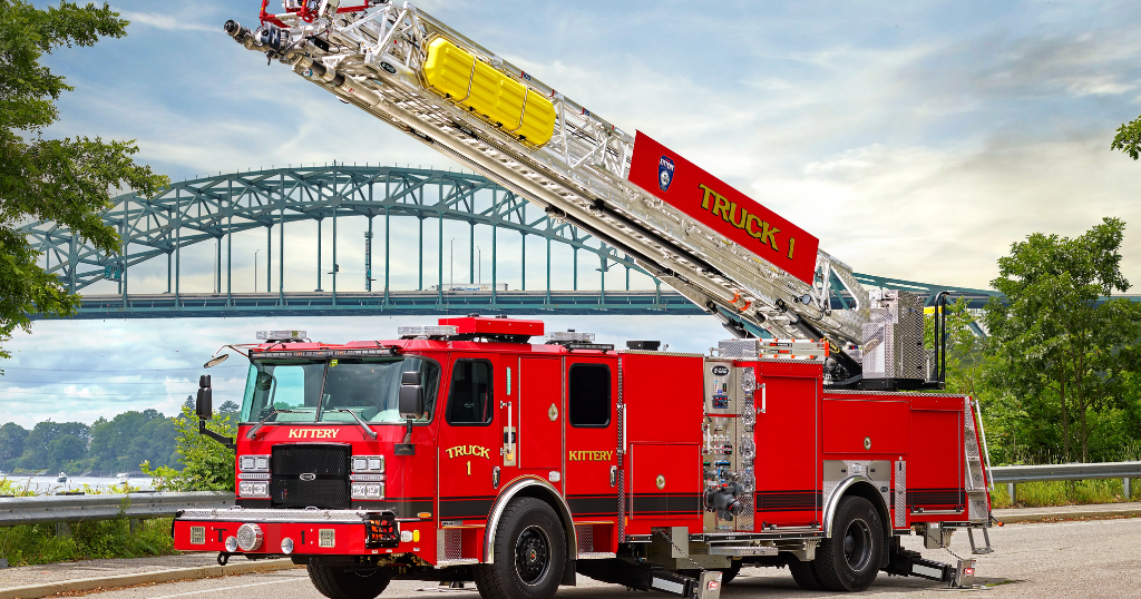 Red fire truck with extended aerial ladder against arched bridge over water