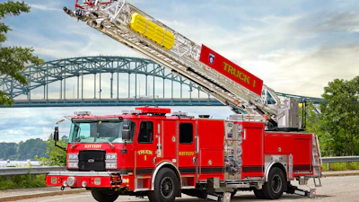 Red fire truck with extended aerial ladder against arched bridge over water