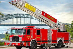 Red fire truck with extended aerial ladder against arched bridge over water