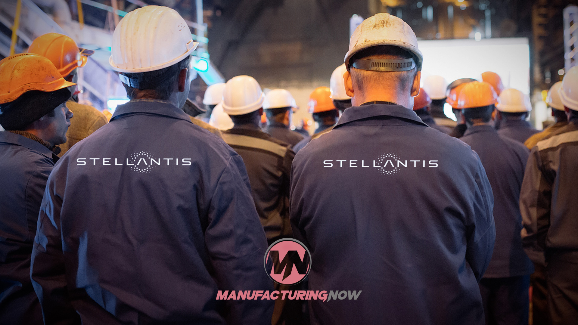 Construction workers wearing Stellantis-branded jackets and hard hats at a nighttime job site