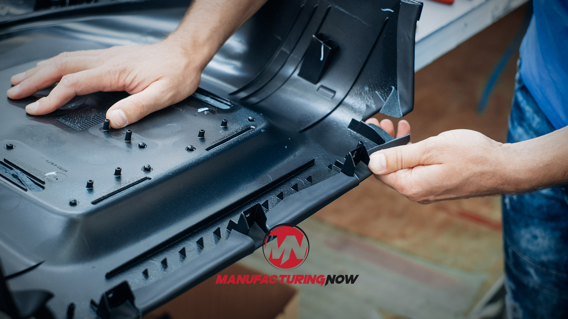 Technician assembling black plastic component with multiple fasteners during manufacturing process