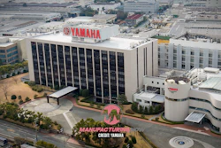 Yamaha manufacturing facility with red logo signage on white rooftop overlooking industrial complex