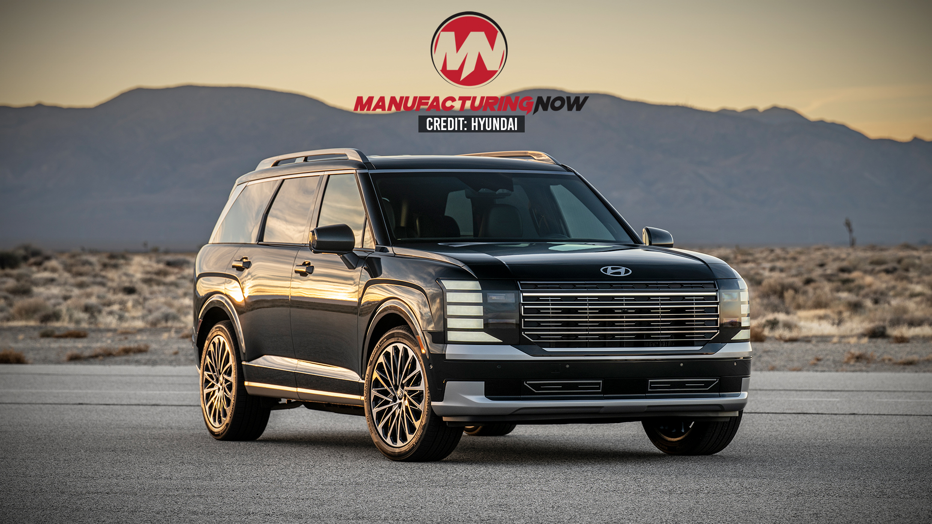 Luxury black SUV with gold wheels displayed in desert landscape at sunset