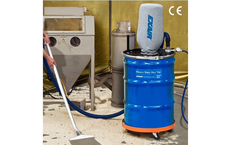 Industrial sandblasting equipment setup with blue EMCO drum unit and gray cabinet blaster in workshop