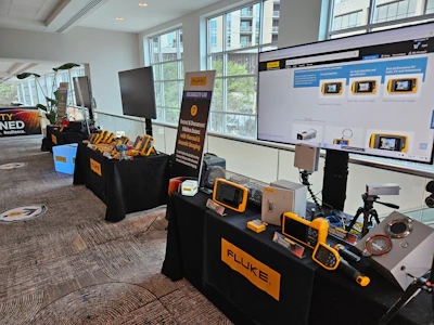 Fluke testing equipment exhibition booth with measurement devices and digital displays in modern office setting