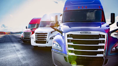 Fleet of colorful semi-trucks parked in a row under blue sky with clouds