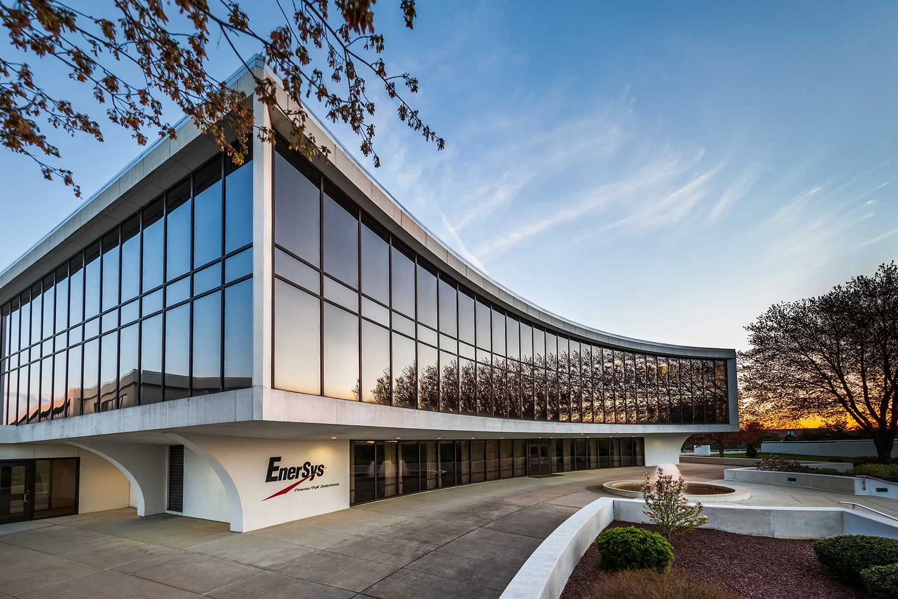 Modern EnerSys corporate headquarters building with curved glass facade and white exterior at sunset