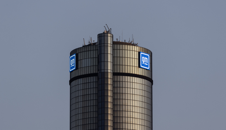 GM General Motors logo on cylindrical tower building against gray sky
