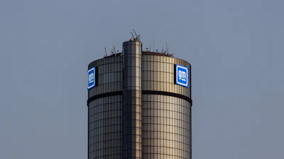 GM General Motors logo on cylindrical tower building against gray sky