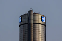 GM General Motors logo on cylindrical tower building against gray sky