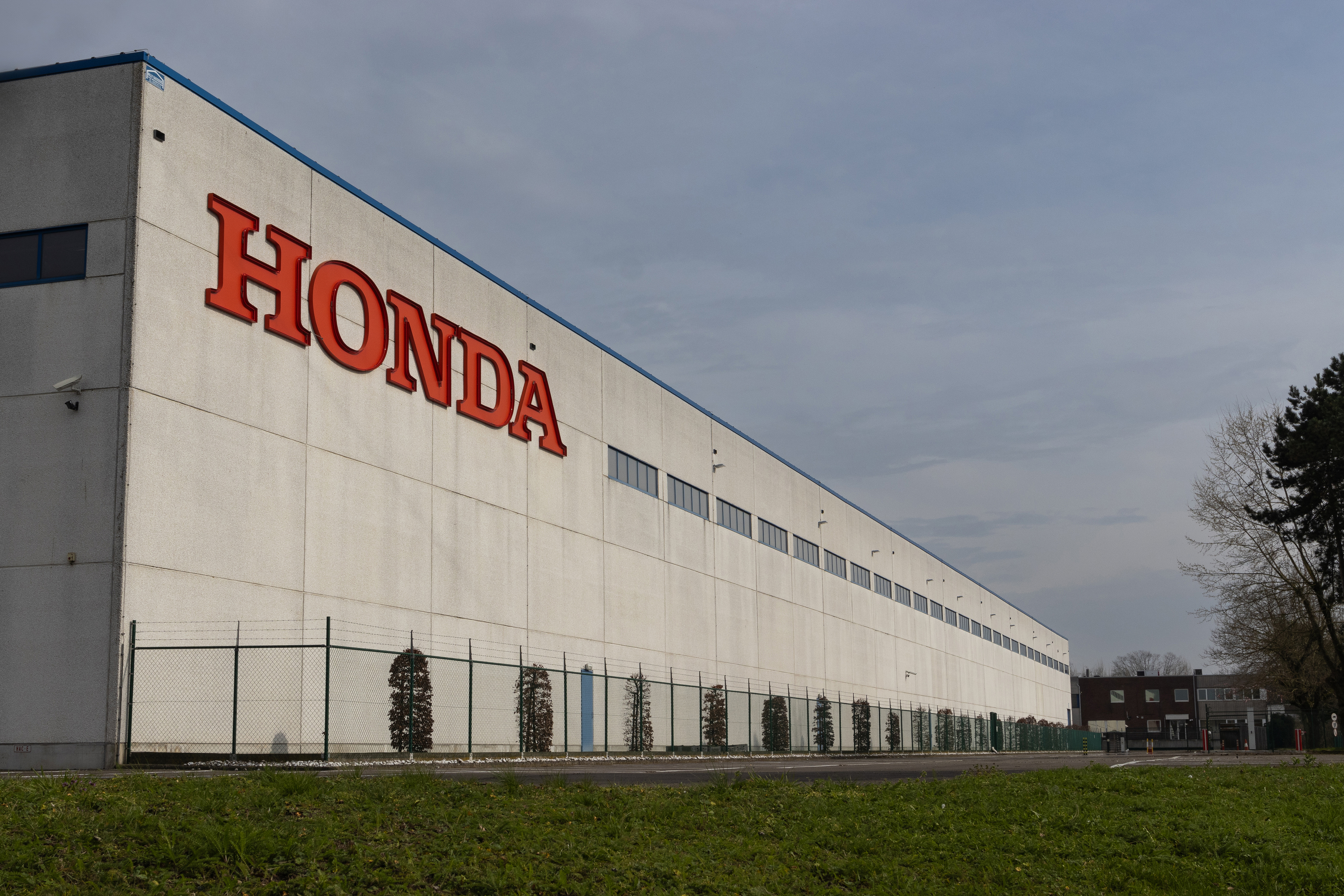 Honda manufacturing facility with red brand lettering on white industrial building facade