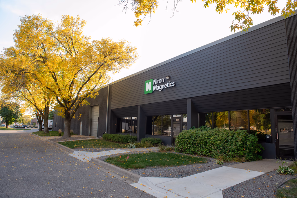 Niron Magnetics storefront with dark modern building facade and autumn trees in background