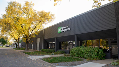 Niron Magnetics storefront with dark modern building facade and autumn trees in background
