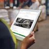 Worker in safety vest viewing maintenance documentation on tablet displaying equipment image