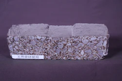 Rectangular composite brick sample with granular texture and smooth coating, labeled with natural material designation