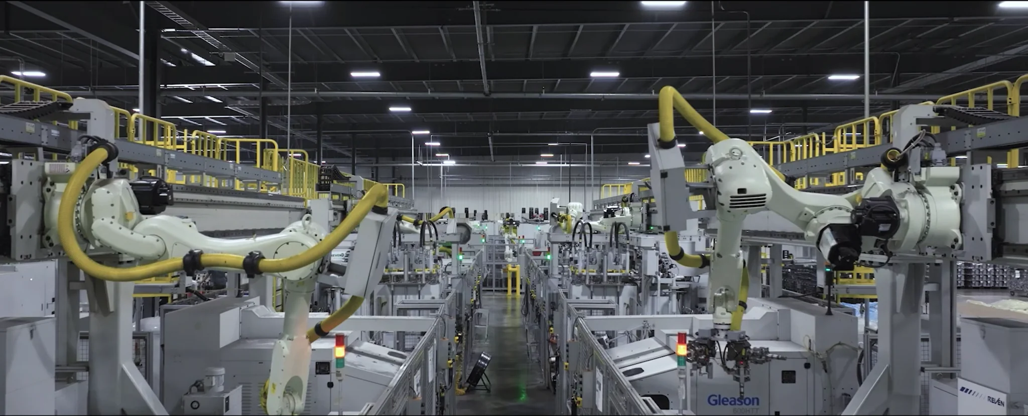 Industrial robot arms on assembly line in modern manufacturing facility with overhead lighting