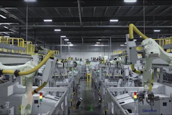 Industrial robot arms on assembly line in modern manufacturing facility with overhead lighting