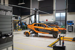 Orange and black hybrid flying car with rotor blade in industrial workshop hangar