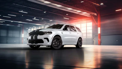 White Dodge Durango with black racing stripes parked in modern garage with dramatic red and warm lighting