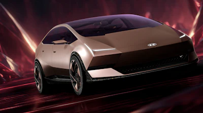 Hyundai concept electric vehicle with sleek silver design and futuristic styling against dramatic red lighting backdrop