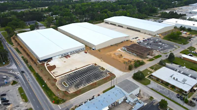 Aerial view of large industrial warehouse facility with white-roofed buildings and parking lot