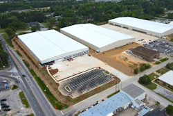 Aerial view of large industrial warehouse facility with white-roofed buildings and parking lot