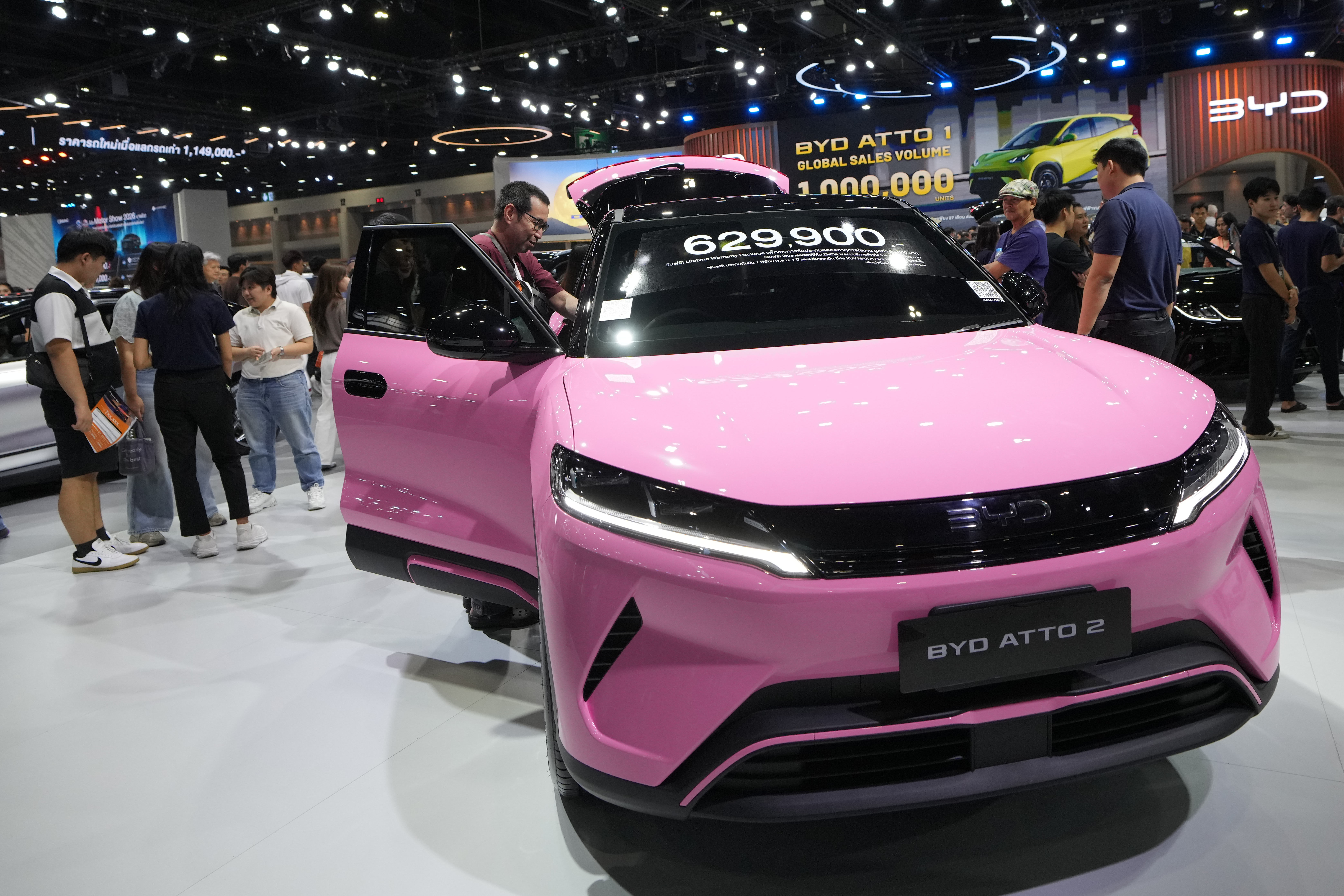 Pink BYD Atto 2 electric vehicle on display at auto show with price tag and visitors