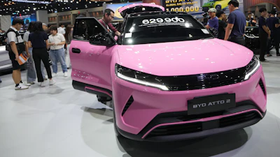 Pink BYD Atto 2 electric vehicle on display at auto show with price tag and visitors