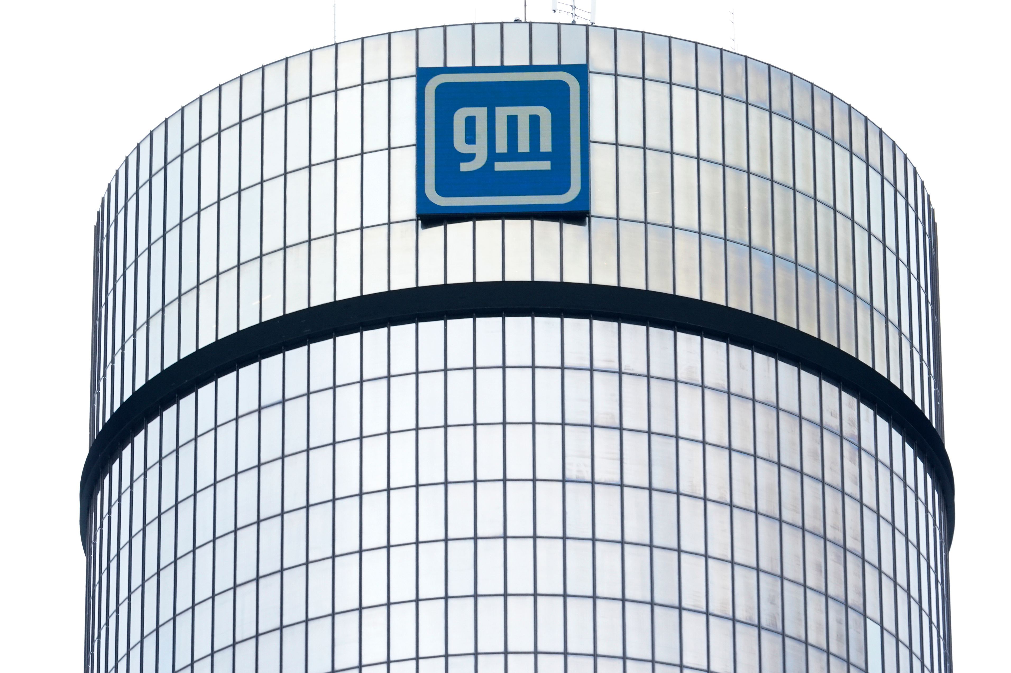 GM logo mounted on cylindrical glass and steel building facade