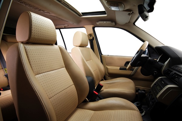 Luxury car interior with beige leather seats, dark steering wheel, and panoramic sunroof