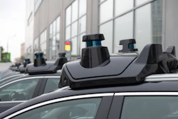 Row of vehicles with black roof racks and cargo carriers parked on urban street with modern building