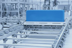 Blue component on industrial conveyor system with metal rails and machinery