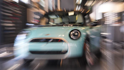 Light blue vintage car displayed in showroom with motion blur effect