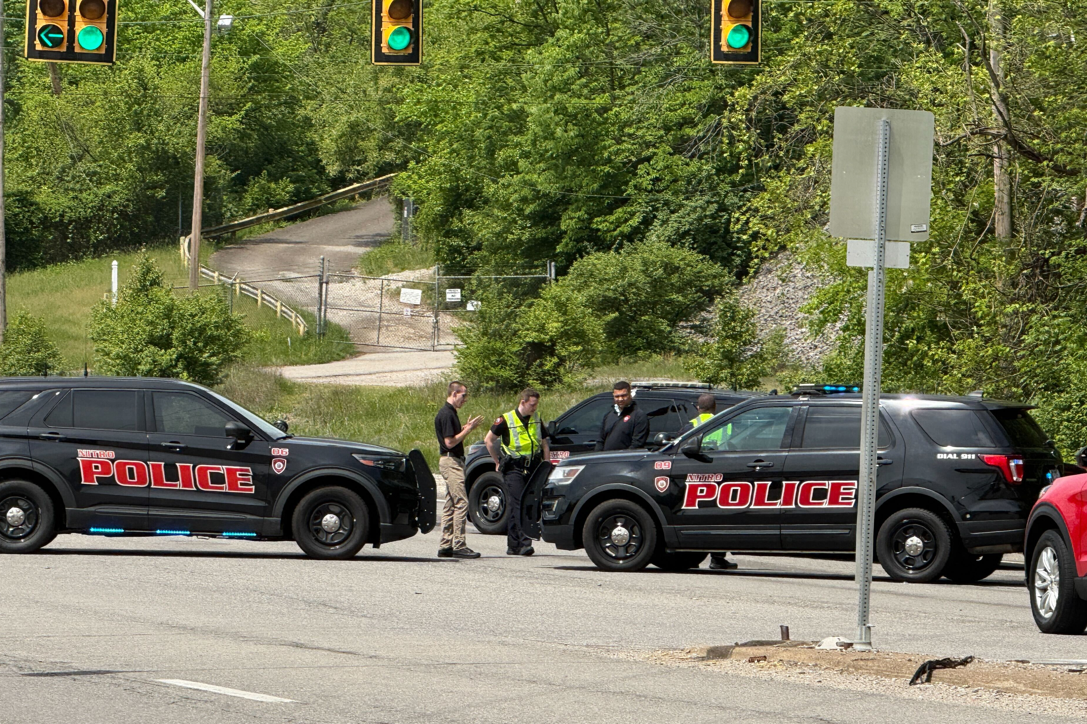 Police officers conducting traffic stop on street with multiple patrol vehicles and traffic lights visible
