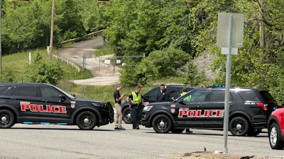 Police officers conducting traffic stop on street with multiple patrol vehicles and traffic lights visible