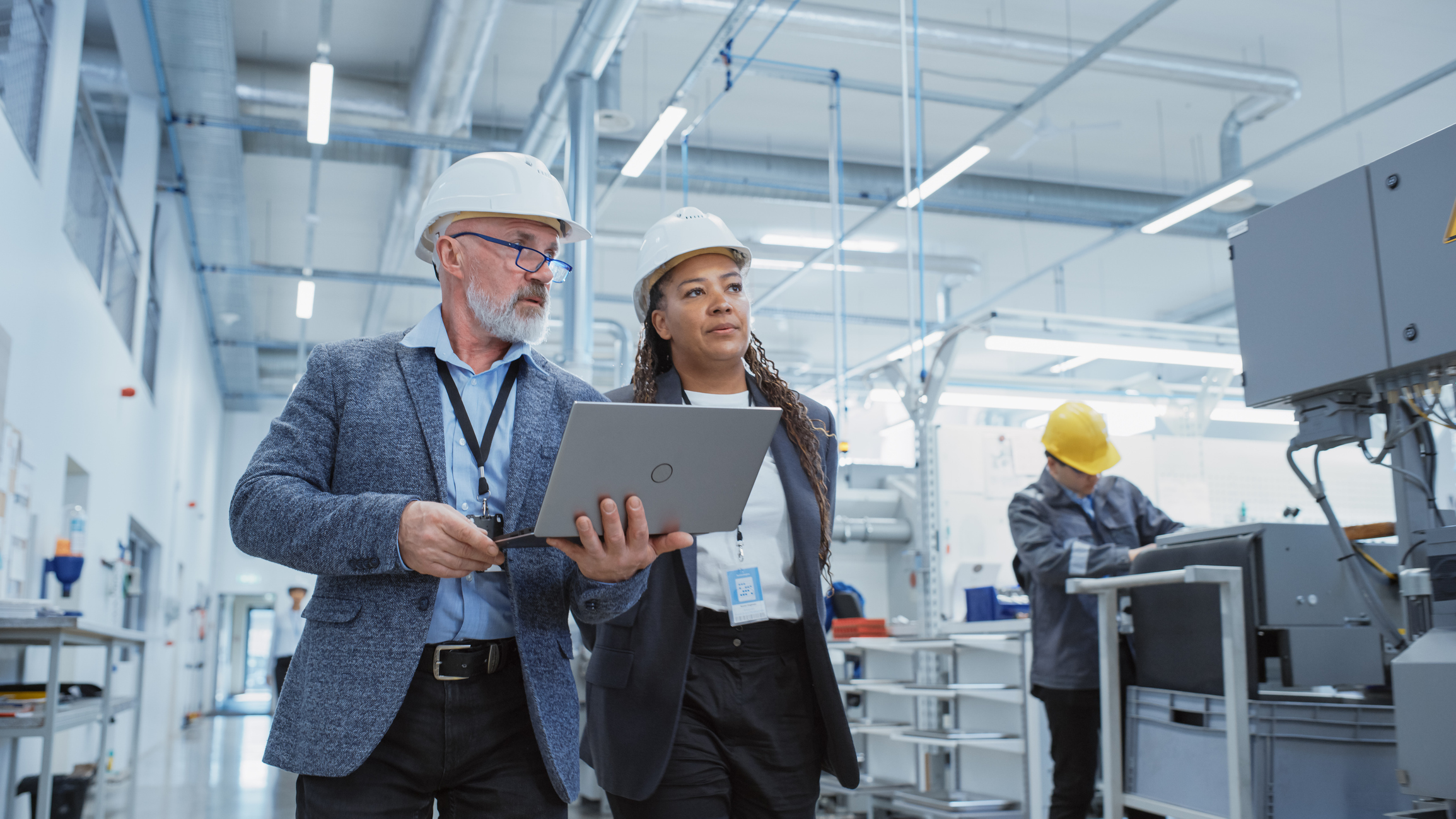 Two professionals in hard hats inspect industrial facility with tablet device