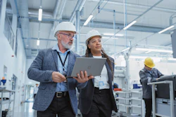 Two professionals in hard hats inspect industrial facility with tablet device